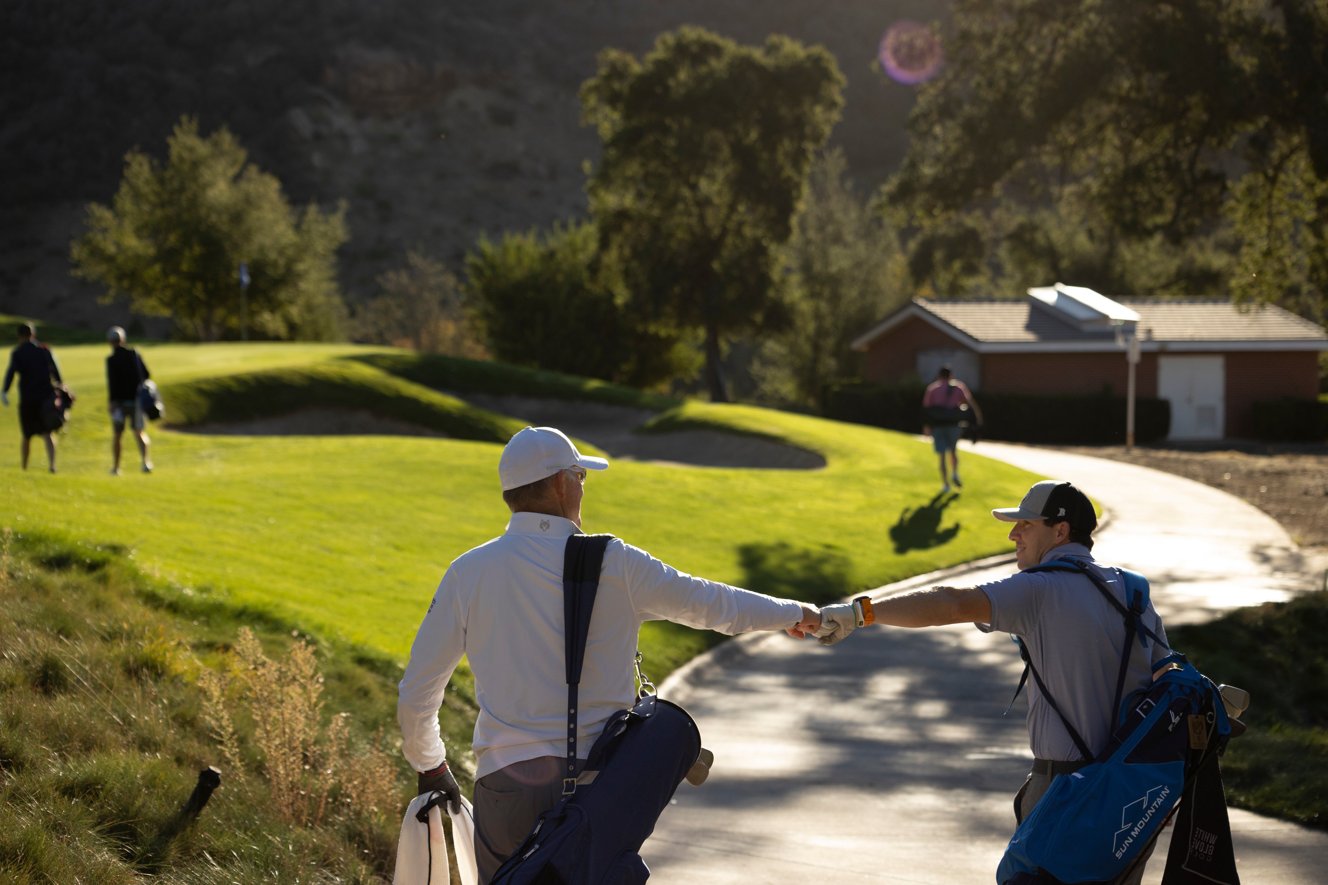 100 Hole Hikers fist bumping on the golf course