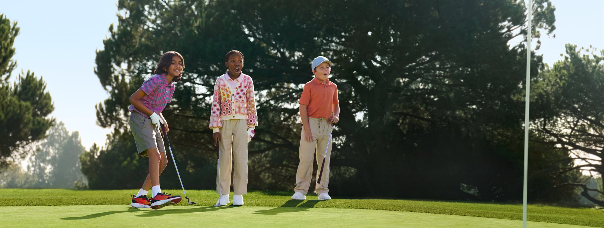 Three kids playing golf