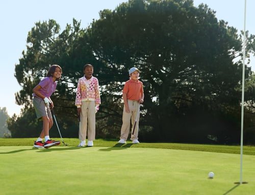 Three kids playing golf
