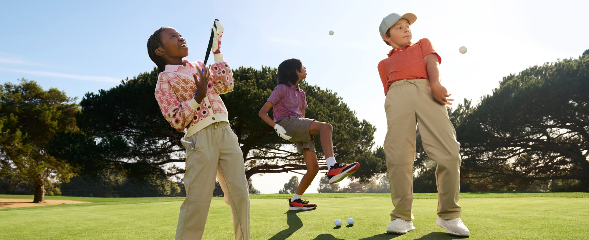 Three youth golfers joyfully play around on a beautifully maintained course