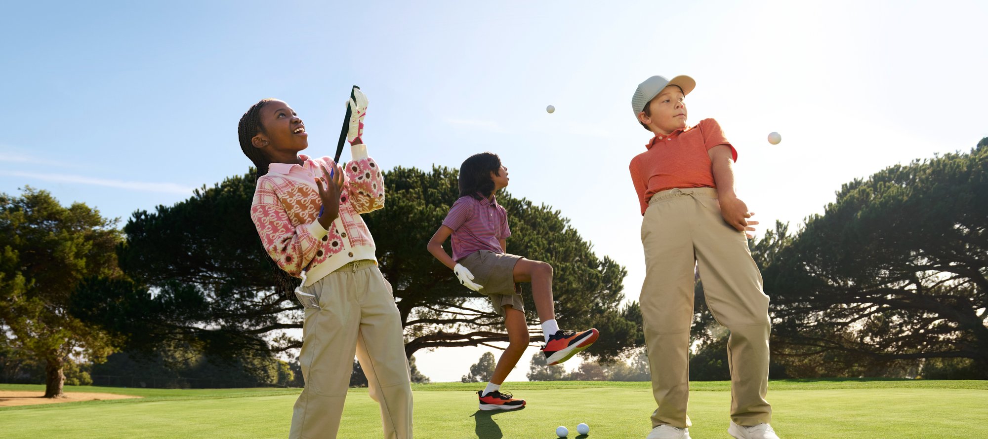 Three youth golfers joyfully play around on a beautifully maintained course