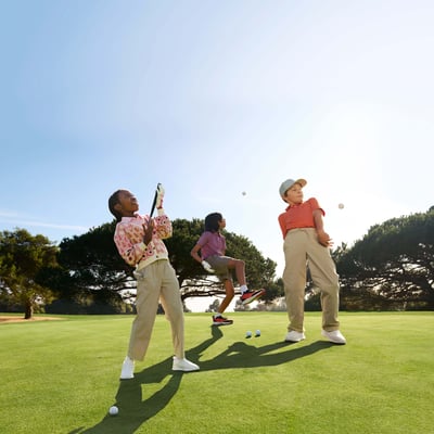 Three youth golfers joyfully play around on a beautifully maintained course