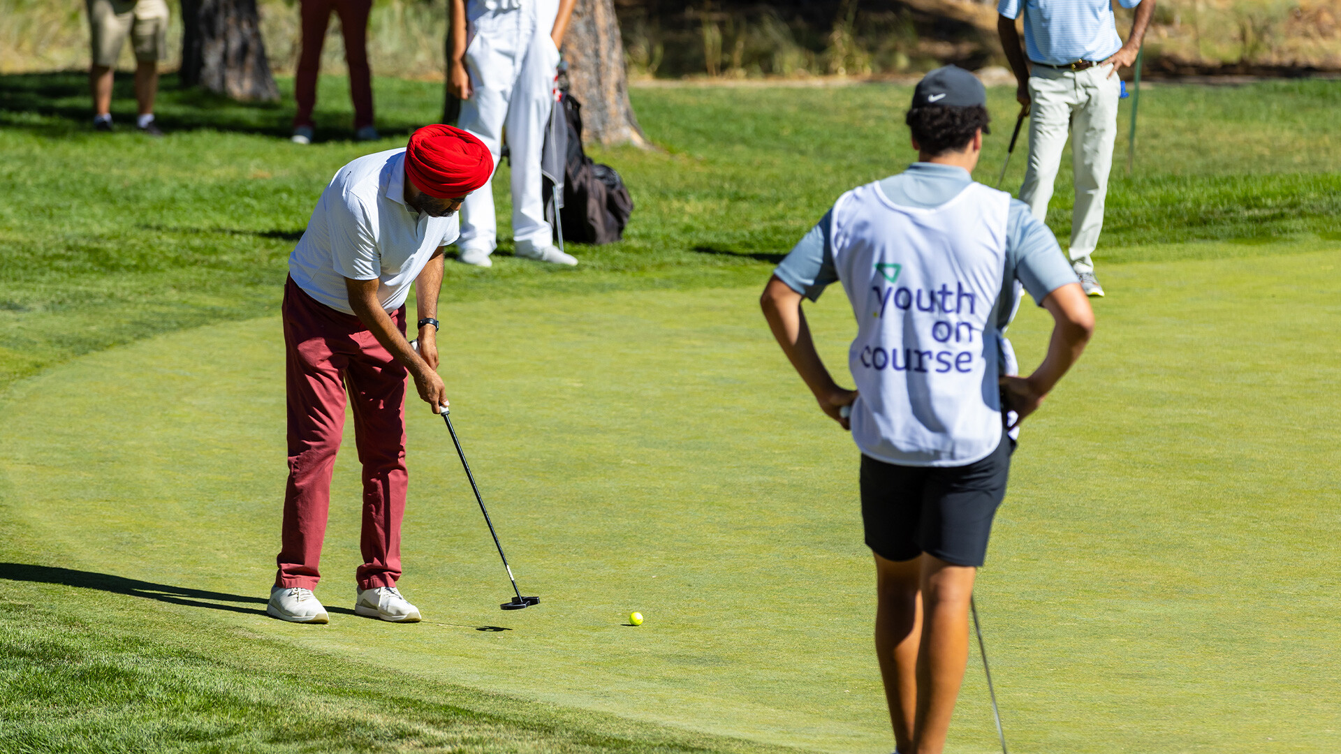 Youth on Course member caddying for amateurs alongside pros