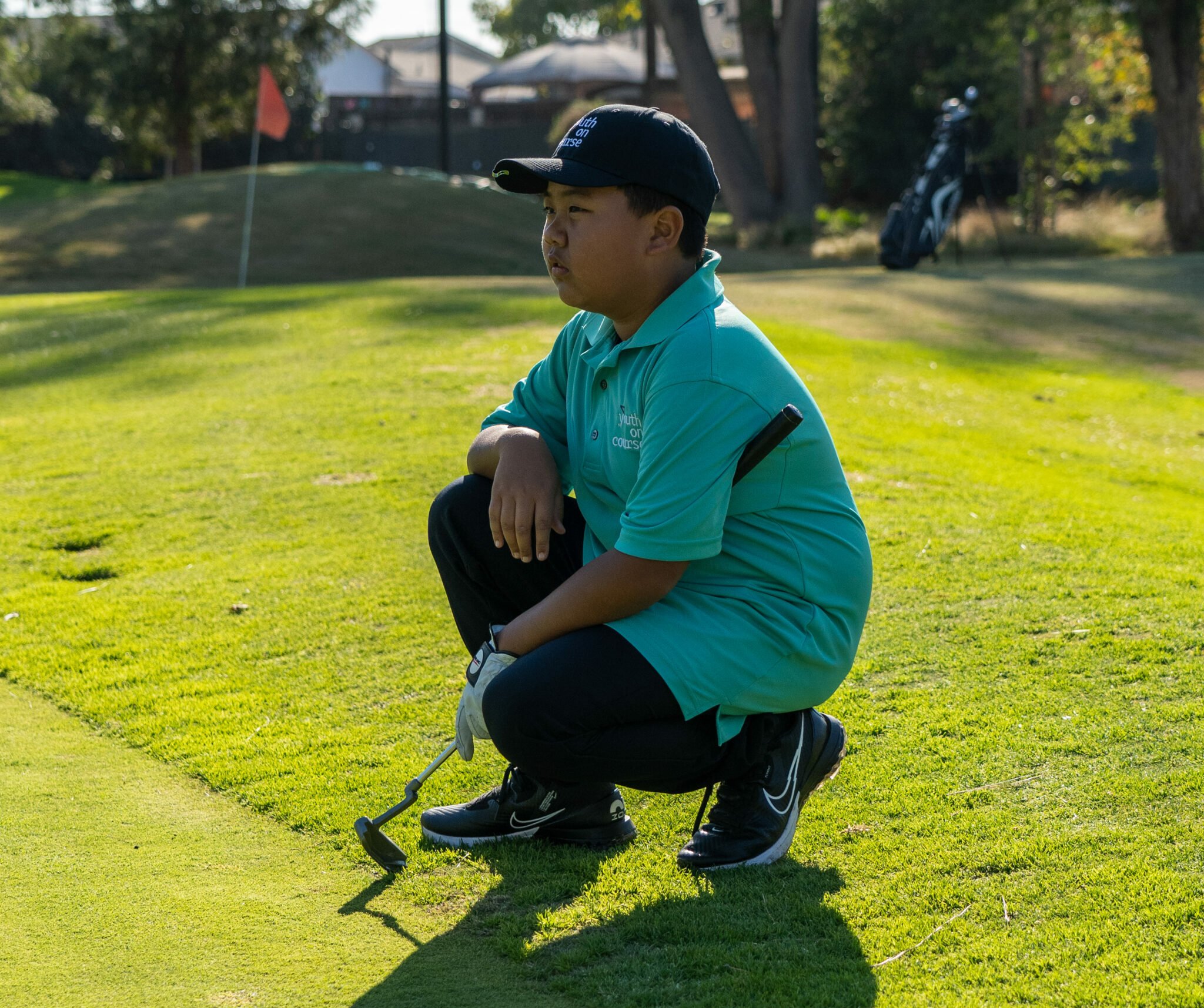Youth on Course member analyzing the green and preparing to putt