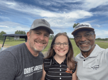 Roberto Correa posing for a picture with a young golfer and her father